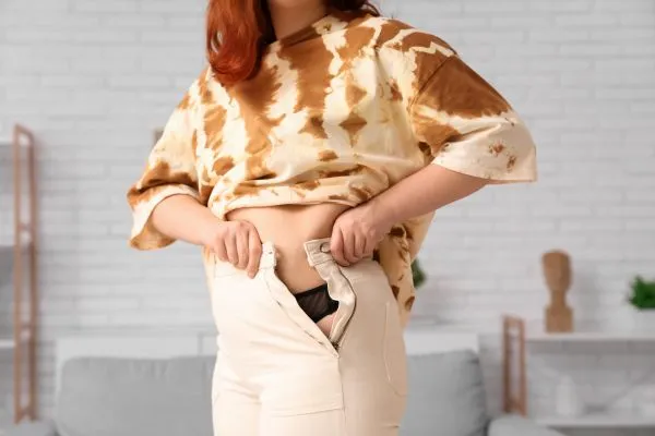 Image of woman trying to do her trousers up after pregnancy weight gain Kirkby in Ashfield